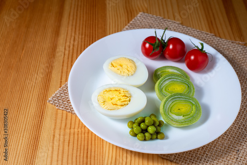 boiled egg, cherry tomatoes, peas and leek on a wooden table in the kitchen