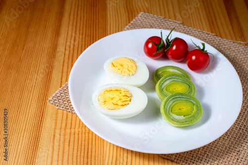 boiled egg, cherry tomatoes and leek on a wooden table in the kitchen