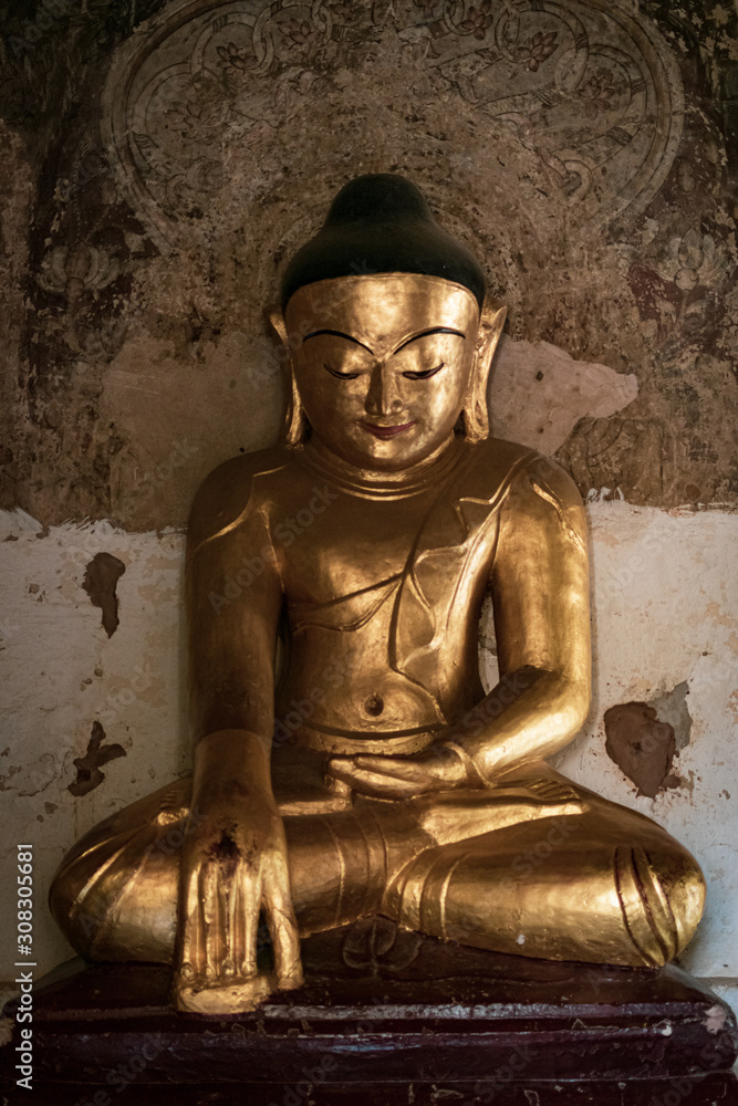 Ancient Golden meditating Buddha statue in one of the atmospheric temples in Old Bagan, Myanmar.