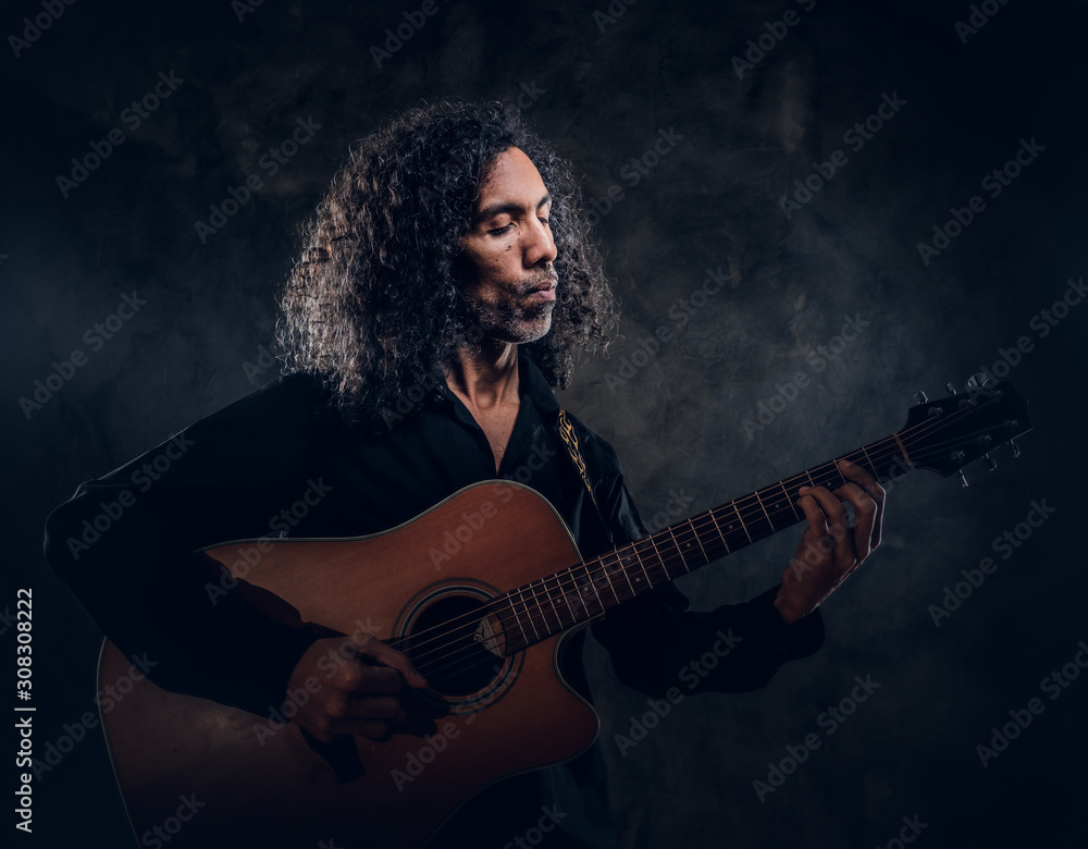 Talented musician is performing with his guitar at dark studio. Talented musician is performing with his guitar at dark studio.