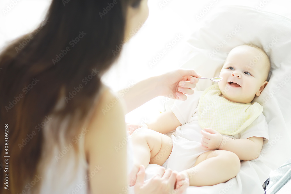 Maternity concept. A young mother feeds her little baby. First lure and breastfeeding. Family in white clothes.