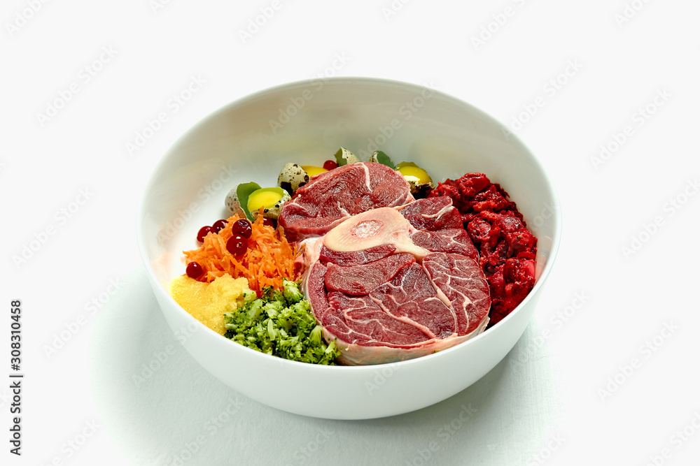 Natural dog food in big white bowl over white background. Beef meat, eggs and vegetables. Close up. Natural dog food in big white bowl over white background. Beef meat, eggs and vegetables. Close up.