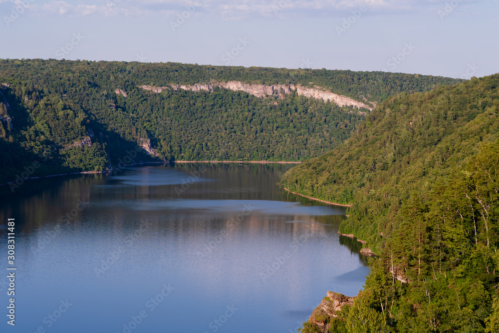 Obraz premium Blue lake in the middle of mountains and forests at sunset.