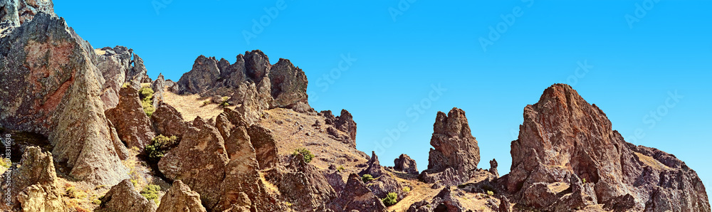 scenic rock formation of volcano mountain landscape against blue sky background. Panorama wide view of karadag mountain range in crimea. Outdoor wild nature panoramic wallpaper