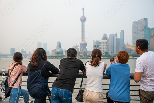 Group of asian tourists contemplate Shanghai skyline from the Bund photo