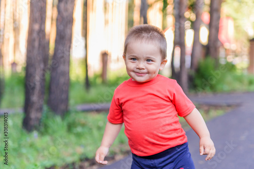 portrait of smiling little boy on the street. cute cheerful baby walking in the Park. happy child © Асель Иржанова
