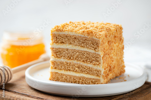 Layer honey cake slice Medovik on white plate, closeup view