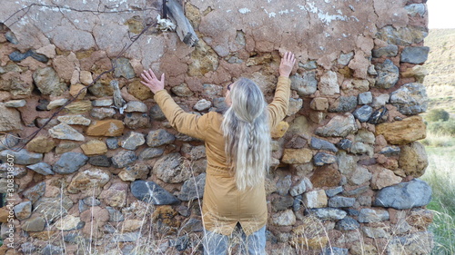 Fotografie Eine Frau betrachtet und betastet die Wand einer alten Ruine