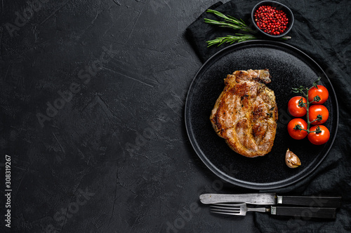 Roast pork steak. Black background. Top view. Space for text