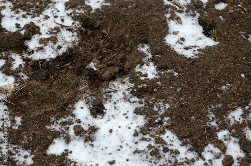 Melting snow on plowed soil. Spring view of plowed field © Oksana