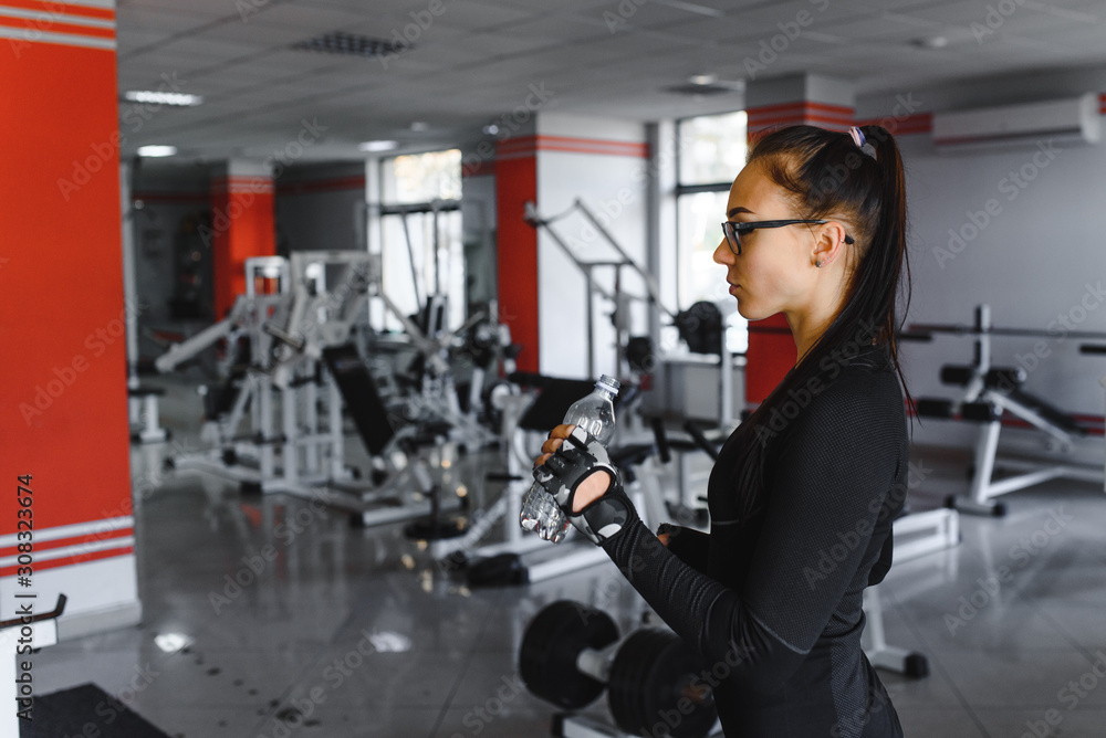 Young woman drinking water after exercising. Fitness gym. Young woman drinking water after exercising. Fitness gym.