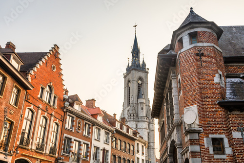 Tall medieval bell tower rising over the street with old european houses, Tournai, Walloon municipality, Belgium