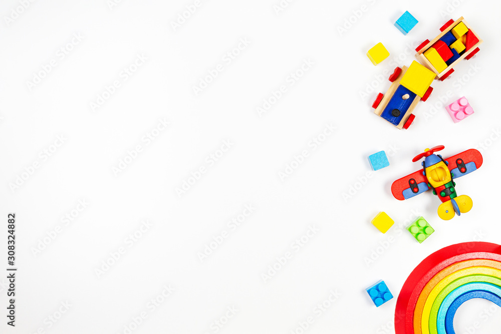 Baby kids toys background. Wooden train, red plane, stacking rings rainbow toy and colorful blocks. Top view, flat lay - obrazy, fototapety, plakaty 