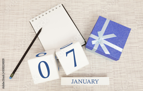 Calendar with trendy blue text and numbers for January 7 and a gift in a box.