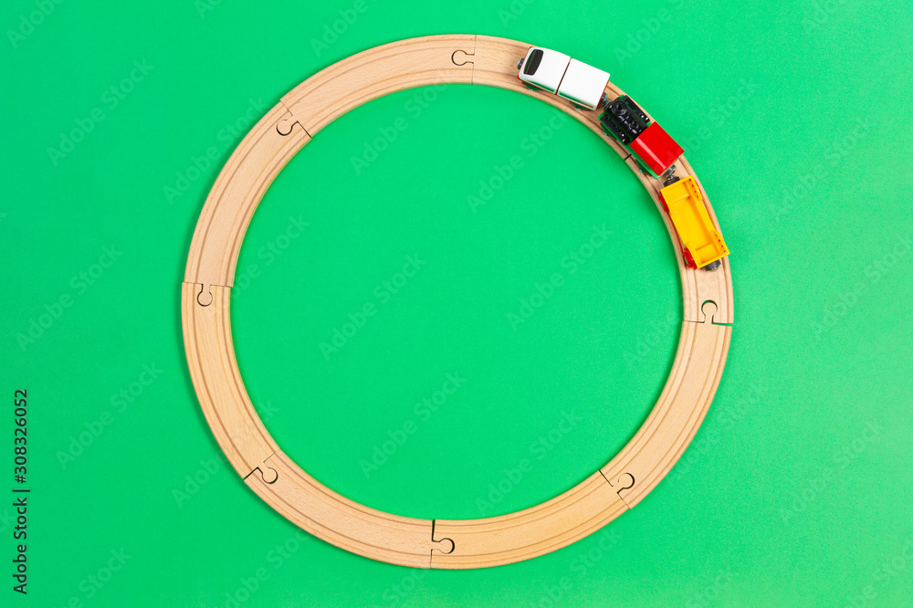 Toy train moves on round wooden railways on light green background. Top view Toy train moves on round wooden railways on light green background. Top view