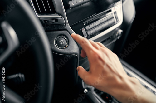 Man driver pushing a start ignition button switch in the modern luxury car.