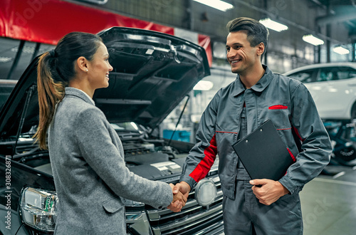 Beautiful businesswoman and auto service mechanic shaking hands. Car repair and maintenance.