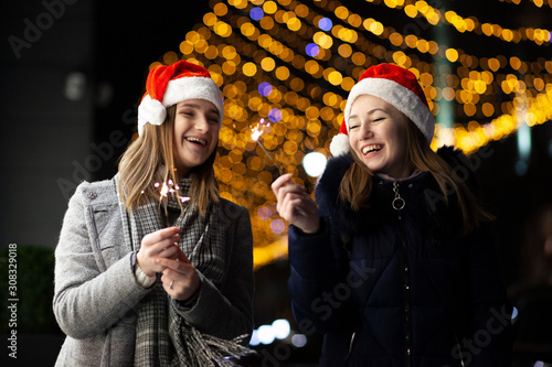girls set fire to sparklers at night on the street, a couple of lesbians celebrate the New Year together
