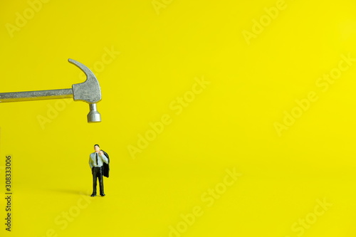 Miniature people concept - desperately businessman (workload shown by the hammer)
