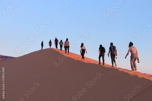 People walking along coral pink sand dunes © Joshua Sukoff