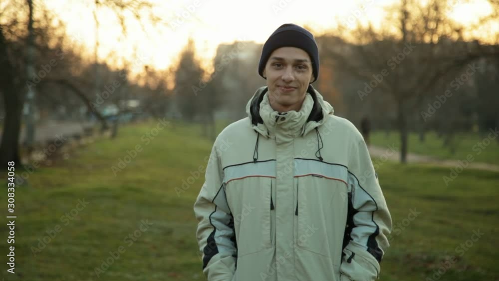 Portrait of handsome young man standing in the park in the evening in a winter Portrait of handsome young man standing in the park in the evening in a winter