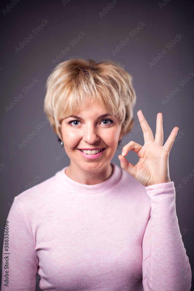 Woman with blond hair showing okay gesture. People and emotions concept Woman with blond hair showing okay gesture. People and emotions concept