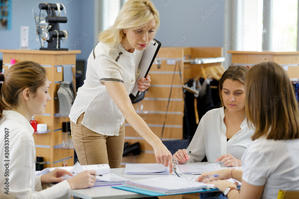 Fototapeta premium supervisor overseeing female trainees doing paperwork in boutique
