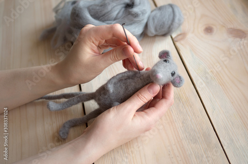 felting wool toy close-up hands on wooden background