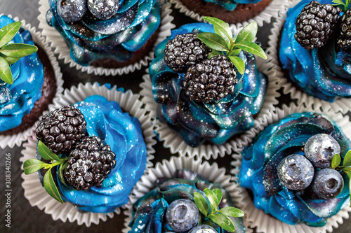 a set of beautiful mouth-watering cupcakes with blue cream and blueberries and blackberries, cakes handmade desserts, close-up