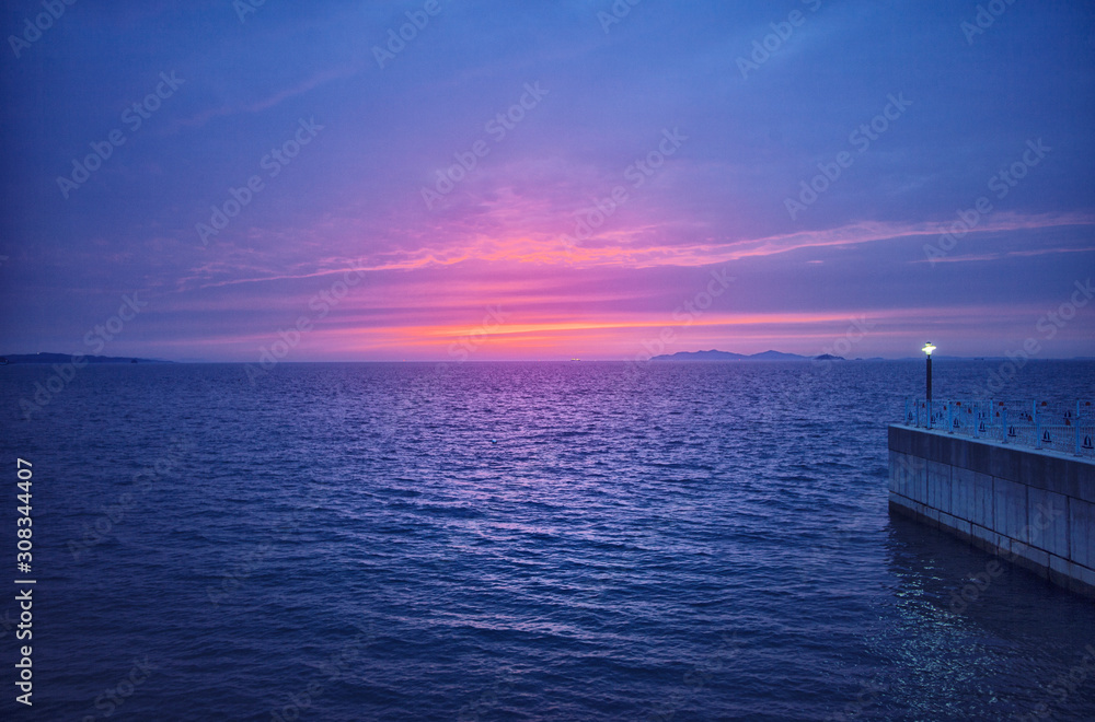 Naklejka premium the horizon of a calm sea with a beautiful red sunset.