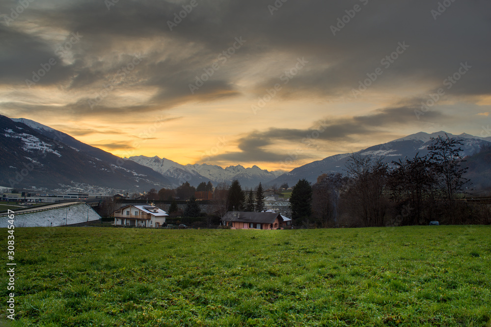 rural landscape, sunset in the mountains with snowy peaks, winter day