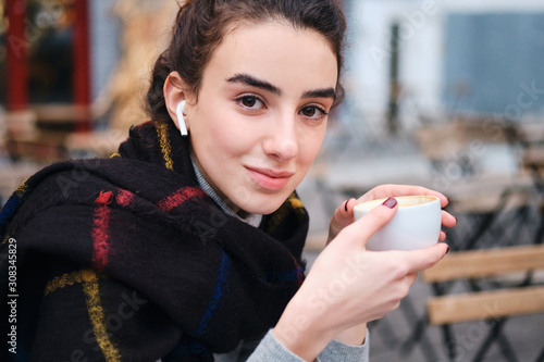 Foto Pretty casual smiling girl with wireless earphones happily looking in camera whi