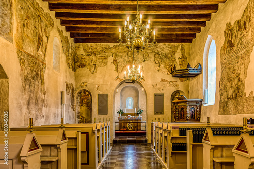 Interior of a medieval church with flat ceiling and romanesque murals