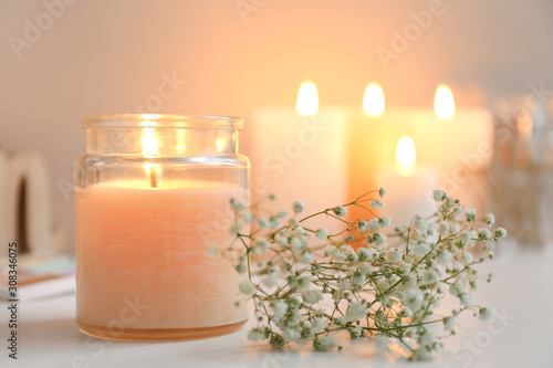 Beautiful burning candle and flowers on table photo