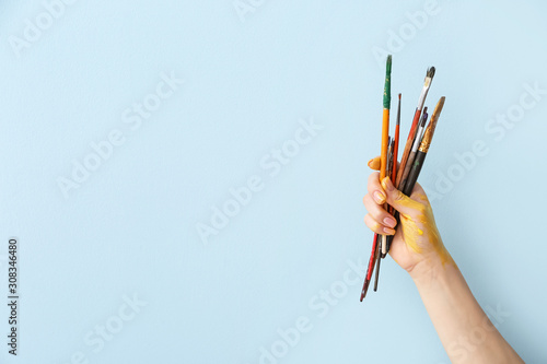 Hand of artist with brushes on color background photo
