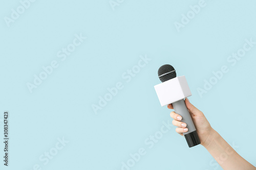 Journalist's hand with microphone on color background photo