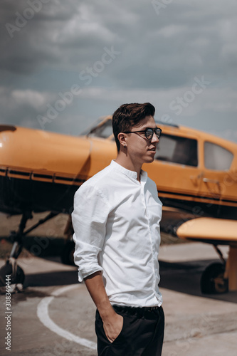 A man standing on the background of a small single engine plane.