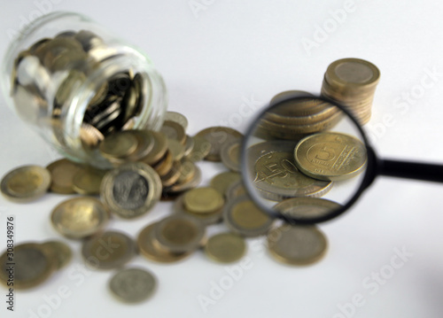 Rising coins, magnifying glass, Pile of mixed iron money coins background