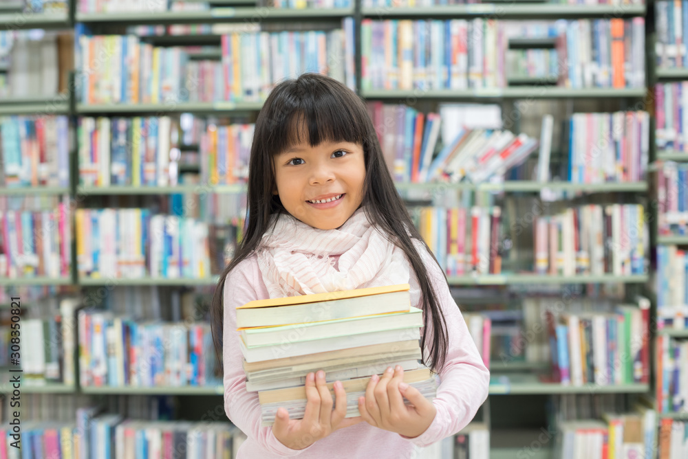 child girl holding a stack of books in the library child girl holding a stack of books in the library