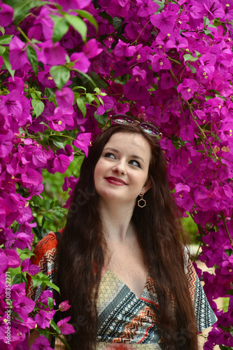 Young brunette caucasian lady smiling under drooping purple flowers