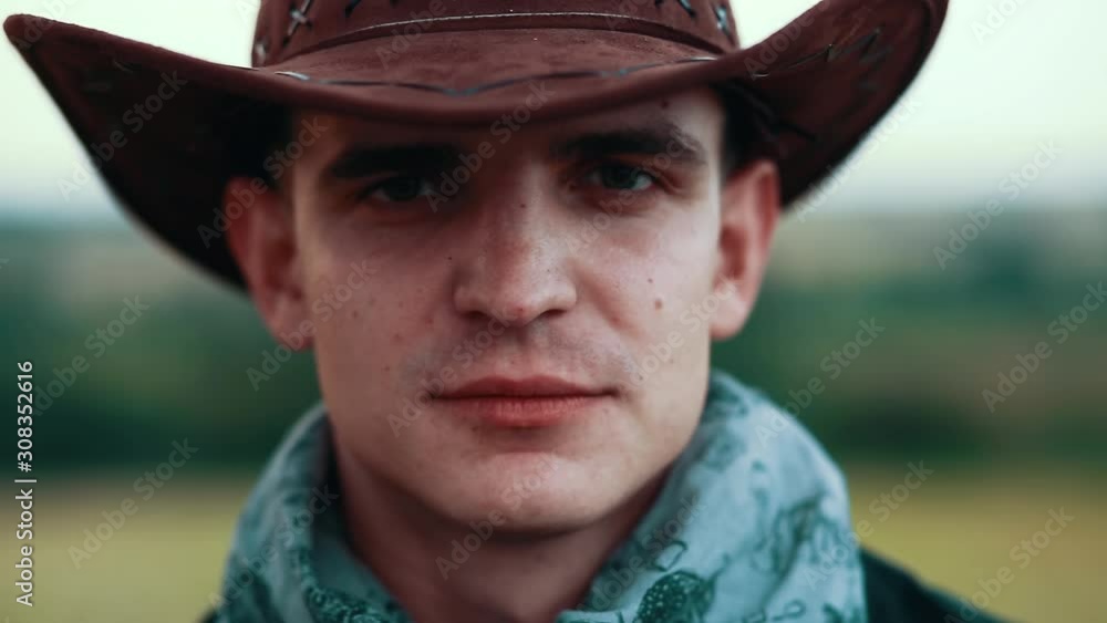 Portrait of young cowboy smoking cigar look at camera serious on field ...