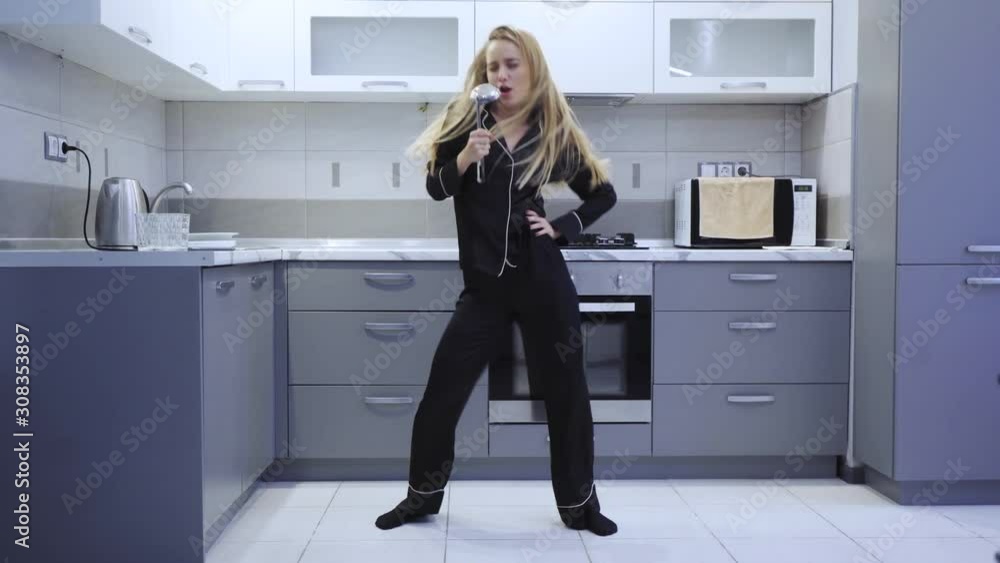 Funny attractive young woman dancing singing uses a ladle in kitchen wearing pajamas at home having fun freedom attractive beautiful music enjoy entertainment happiness pleasure close up slow motion Funny attractive young woman dancing singing uses a ladle in kitchen wearing pajamas at home having fun freedom attractive beautiful music enjoy entertainment happiness pleasure close up slow motion