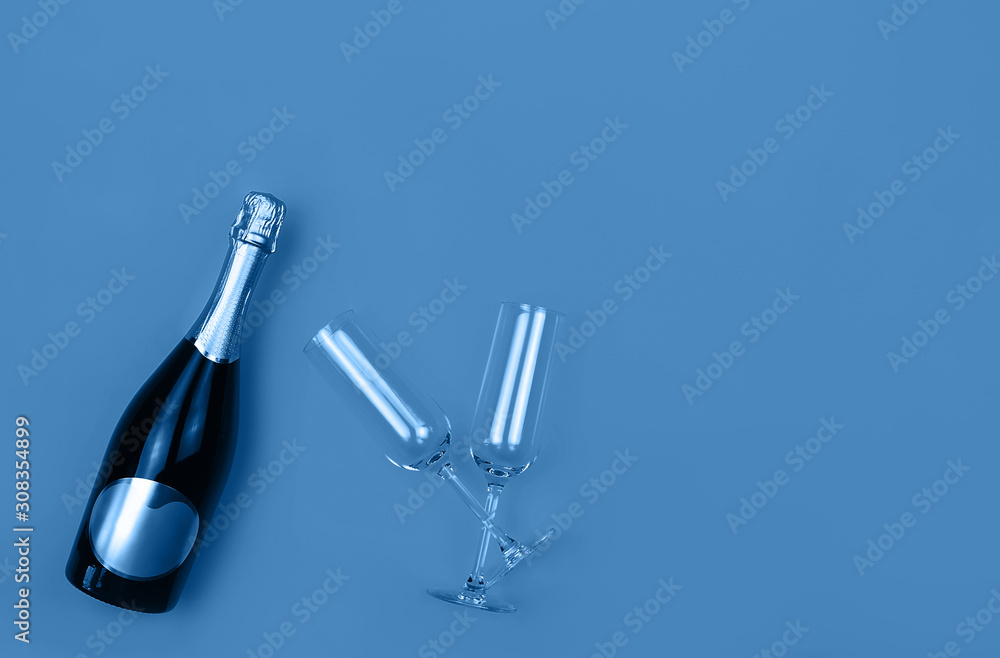 Champagne bottle and glasses on trendy blue background with place for text. Holiday concept. Flat lay style. Mockup for your web banner design. Champagne bottle and glasses on trendy blue background with place for text. Holiday concept. Flat lay style. Mockup for your web banner design.