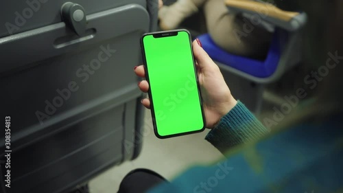 Young woman hold use green screen phone sitting in bus touch telephone public communication vertical smartphone adult finger chroma urban cellphone application digital scrolling slow motion