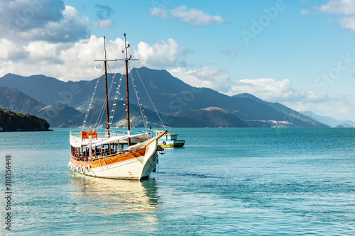 Schooner in big island (Ilha Grande), sea of Angra dos Reis bay with beautiful large mountains in the background, beach holidays on the coast of Rio de Janeiro, Brazil photo