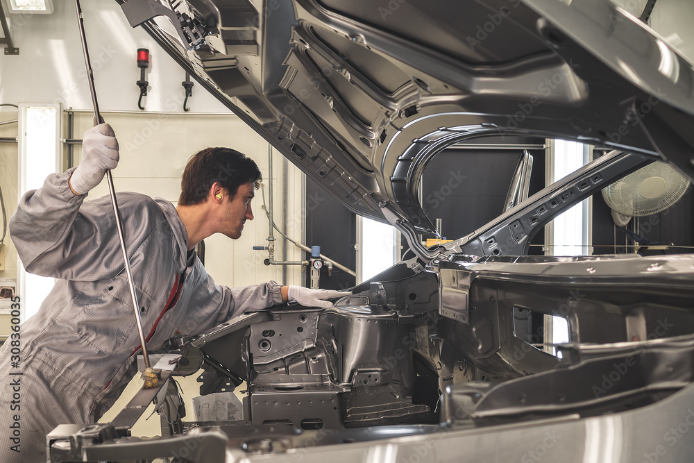 The employee of shop of painting of a body of the car checks quality. production line The employee of shop of painting of a body of the car checks quality. production line