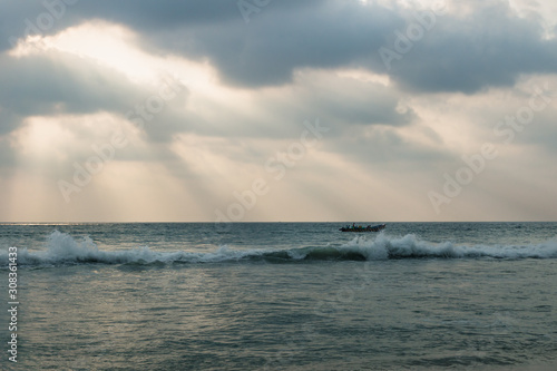 Fishing boat behind the waves of the ocean with sun rays  Varkala  India