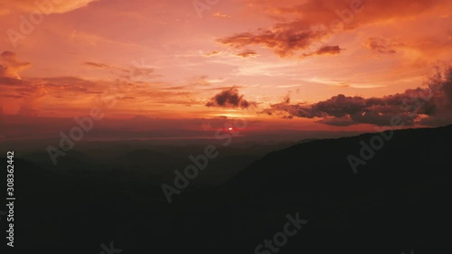 Beautiful 4K aerial drone shot of an epic sunset at Monteverde National Park / Cloud Forest in Costa Rica. The sun gives warm red color to the sky and the jungle rain forest. photo