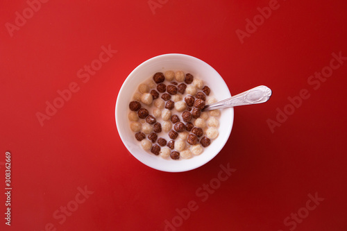 the concept of a delicious and healthy Breakfast, healthy food, advertising chocolate balls with milk. plate, baby food and milk on red background. Copy space