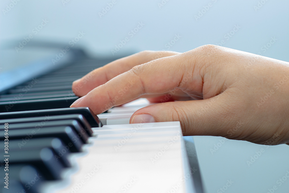Fototapeta premium Male hand playing a keyboard piano during the day light